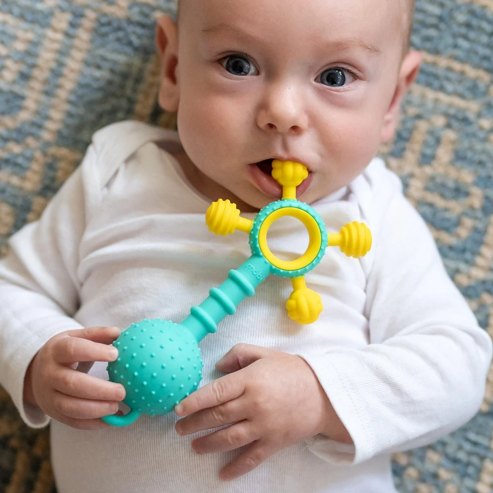 Sensoryczny silikonowy gryzak dla niemowląt Mobi Gumlii z grzechotką i silikonową zaczepką. Ergonomiczna ażurowa grzechotka z silikonu spożywczego wolnego od BPA dla noworodków od pierwszych dni życia 0m+, ulga na ząbkowanie i prezent na wyprawkę.